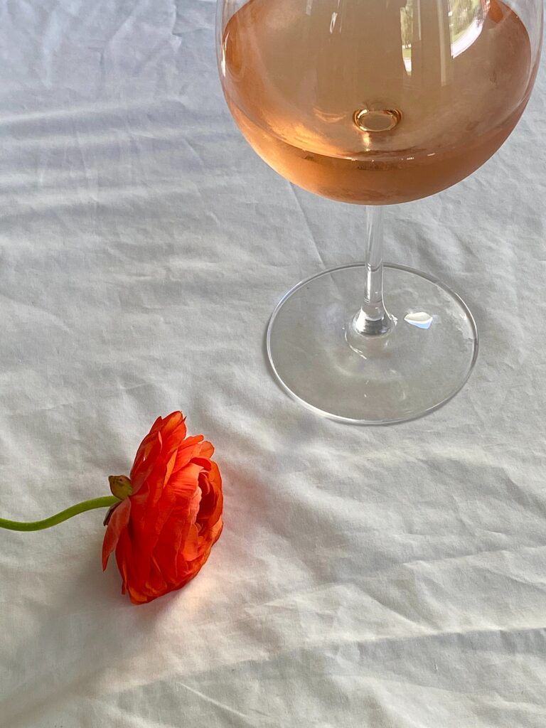 wine on white sheet with red rose beside