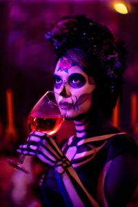 Person in halloween costumer drinking wine, halloween dinner party