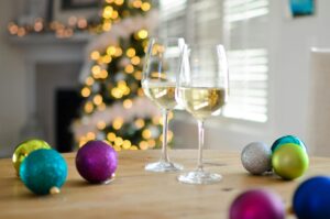 wine glasses on table, baubles on table and tree in background