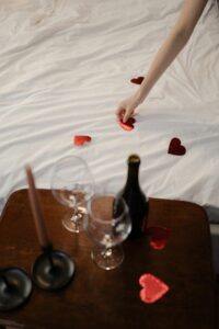 Valentines day, Wine on table, heart petals on bed